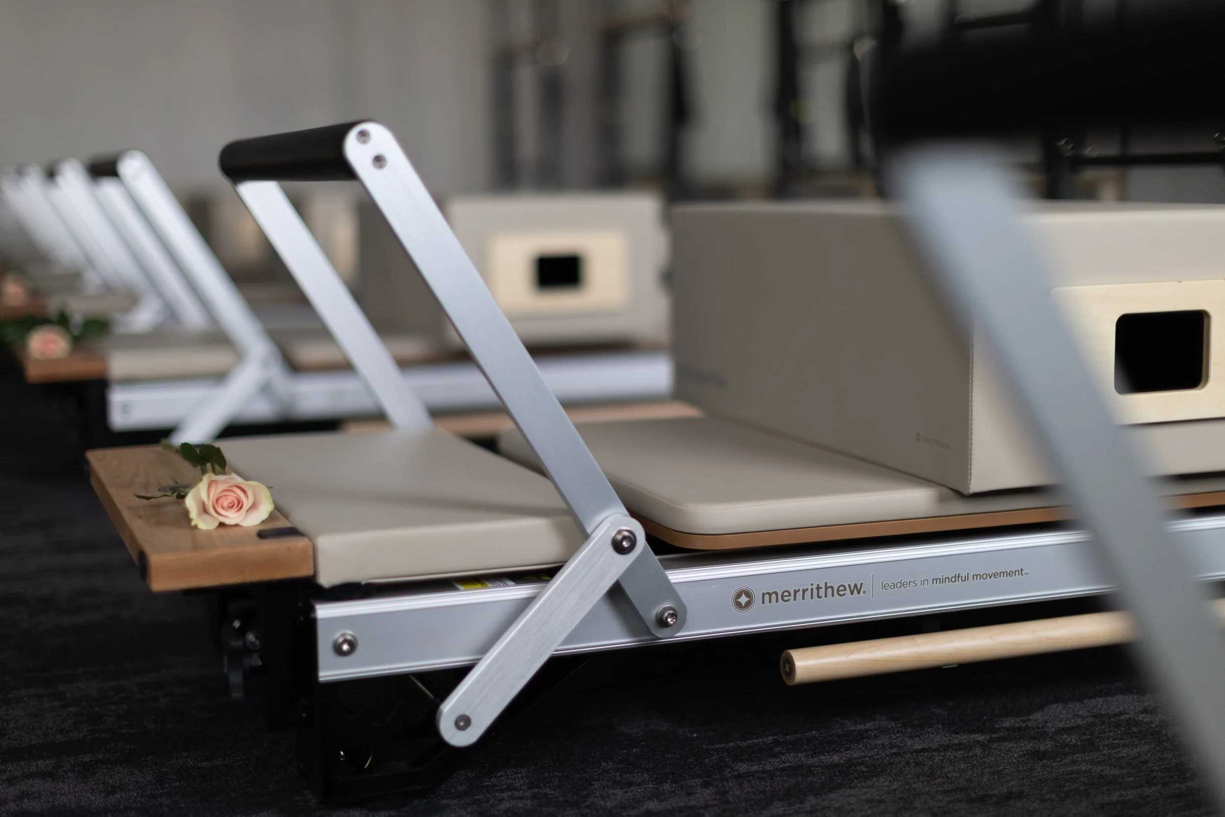 A yoga mat on a Merrithew reformer machine with a pink rose on the mat.