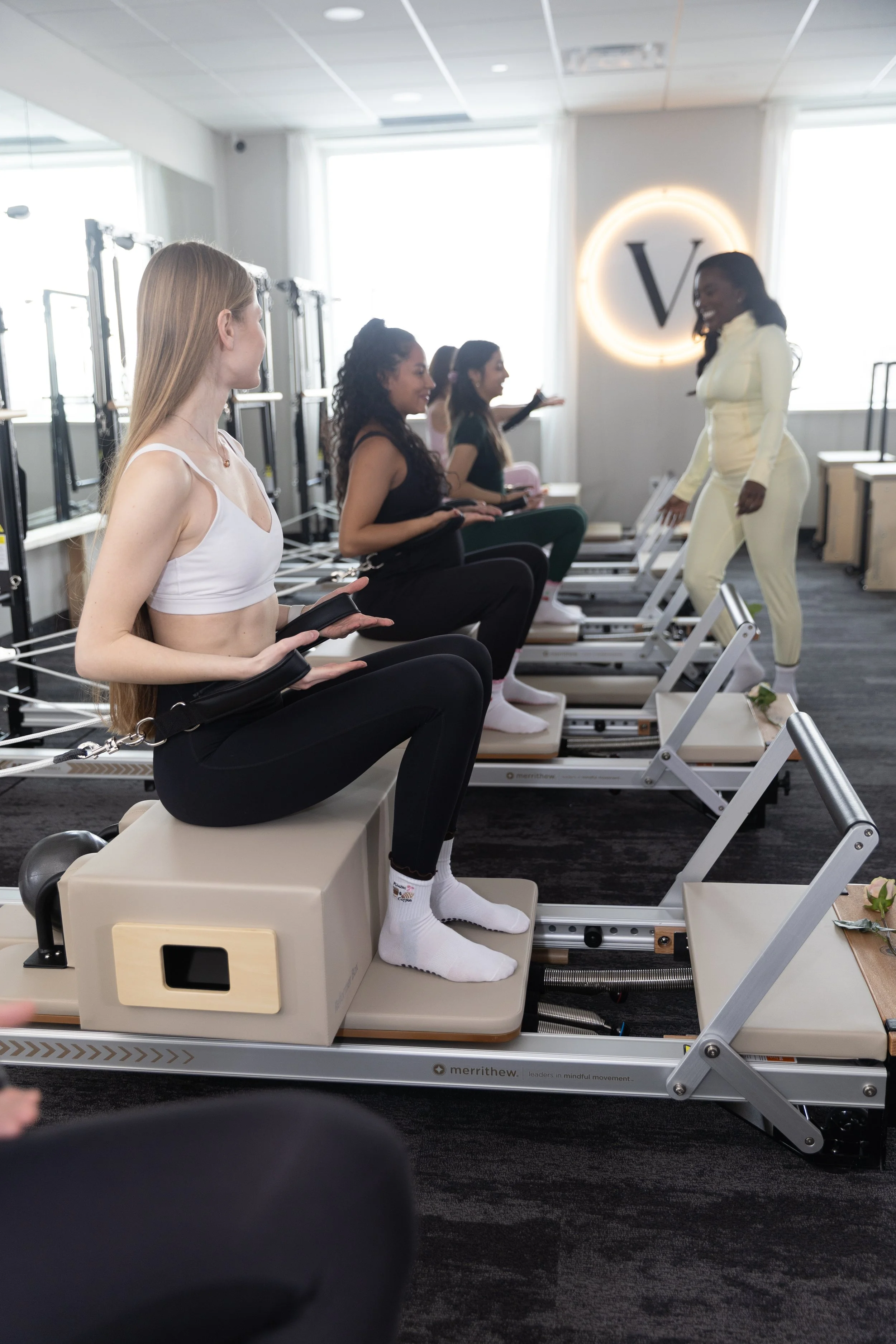Women participating in a barre workout class with instructor demonstrating in front of the class in a fitness studio.