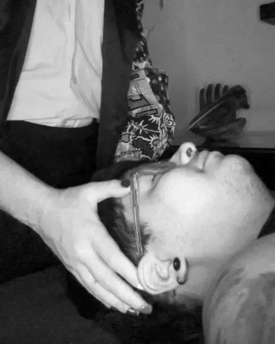 Calla has her hands placed on a clients head to transfer Reiki from her hands to their body