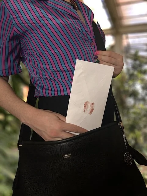 transwoman postal worker placing an envelope sealed with a kiss inside of her messenger bag