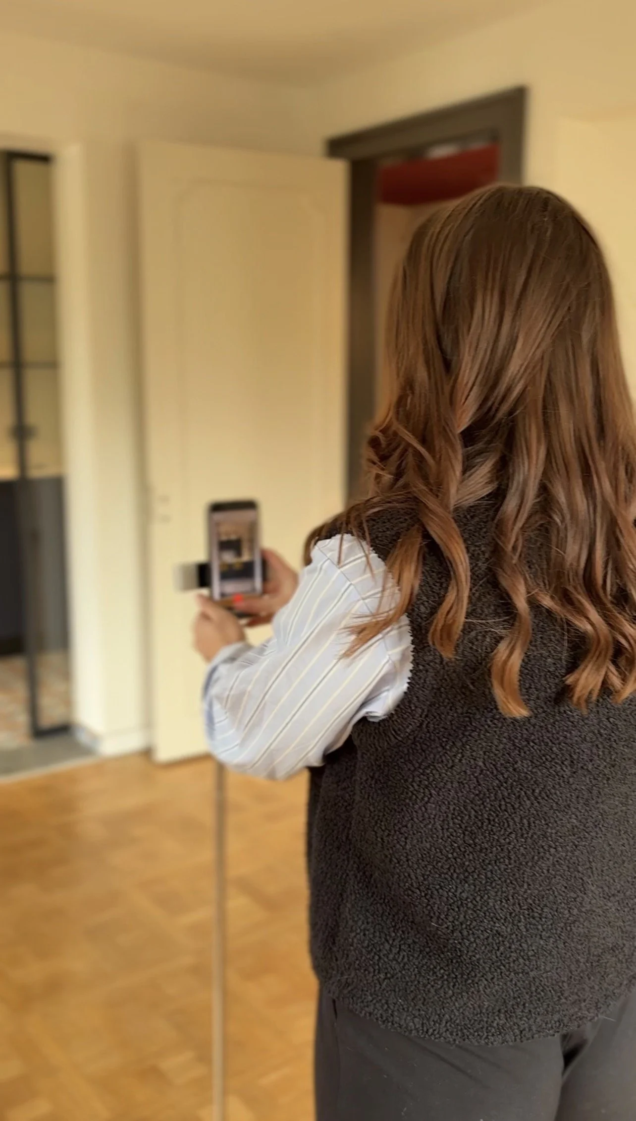 Une personne écrit dans un carnet à lignes avec un stylo, à côté d'un ordinateur portable, d'un téléphone portable, et de lunettes sur une table blanche.