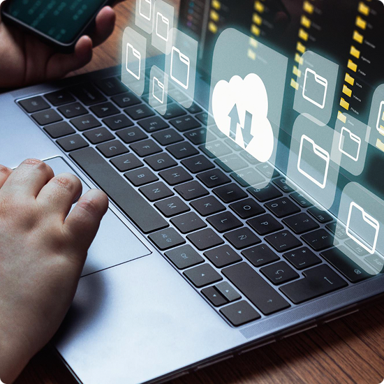 Person using a laptop with virtual cloud storage icon and file folders displayed above the keyboard.