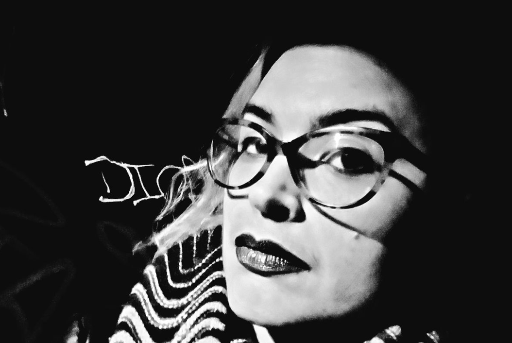 An intense black and white image of the author wearing dramatic lipstick and tortoiseshell glasses