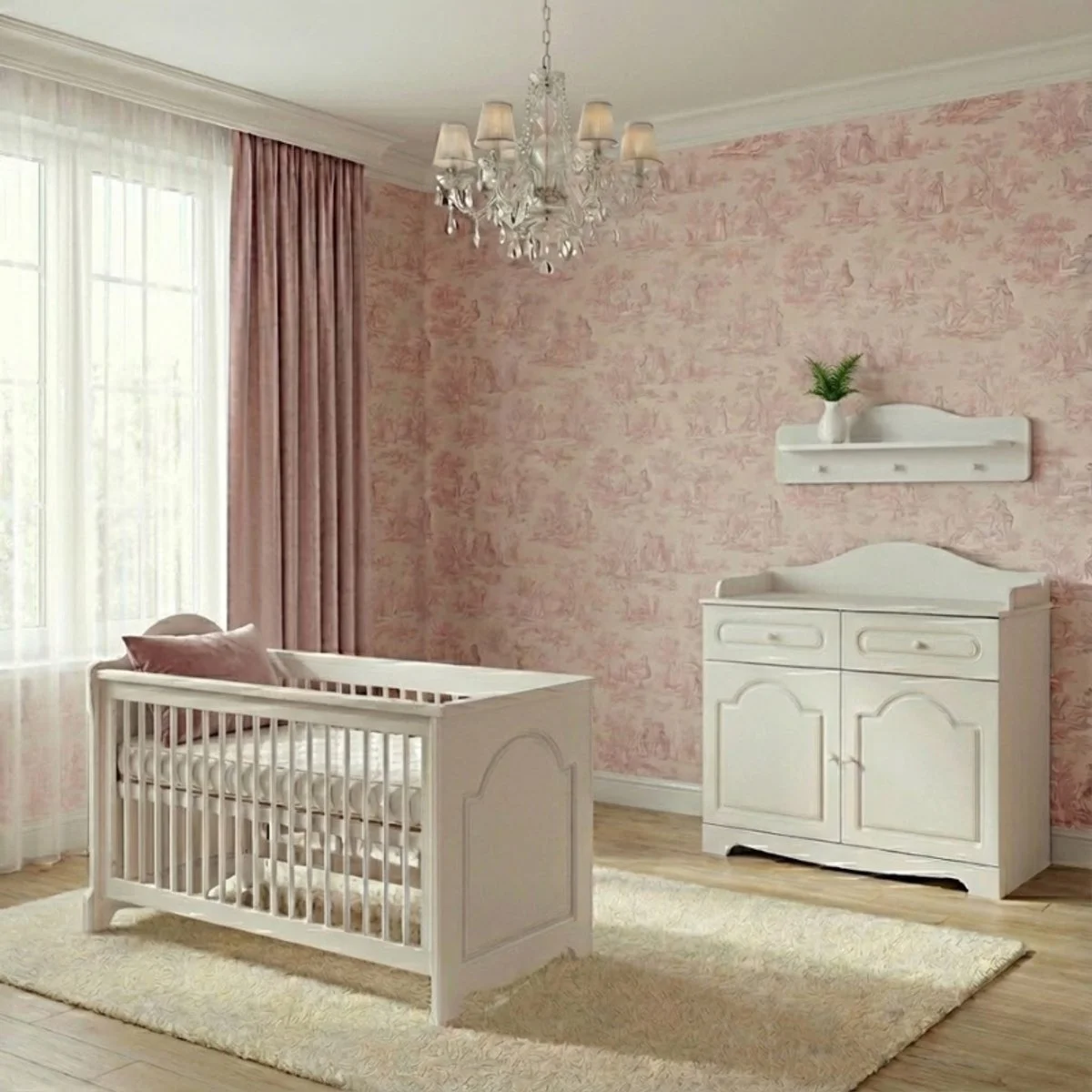 A nursery room with pink patterned wallpaper, a white crib with pink cushions, a white changing table, a wall-mounted shelf with a white vase and green plant, a chandelier, and large window with sheer white curtains and pink drapes.