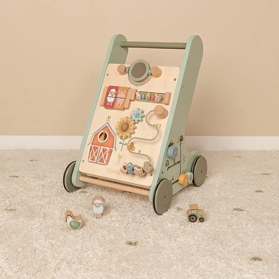 A wooden toy barnyard activity walker with wheels, featuring a white and pastel green color scheme, includes wooden farm animals, a gear, a tractor, and other farm-themed toys on a beige carpet.