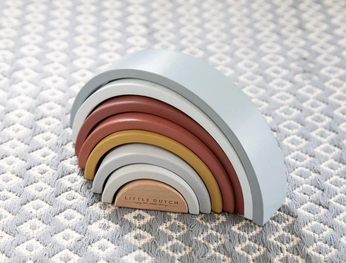 Colorful wooden rainbow stacking toy on a patterned gray carpet.