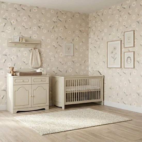 Nursery room with floral wallpaper, a white crib, a changing table with a teddy bear, and framed botanical artwork on the wall.