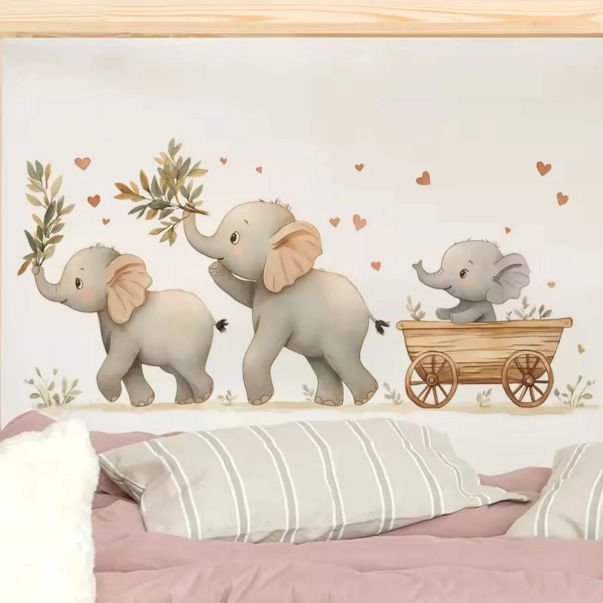Decorative wall art with three gray elephants, two carrying leafy branches and one sitting in a wooden cart, surrounded by small red heart illustrations.