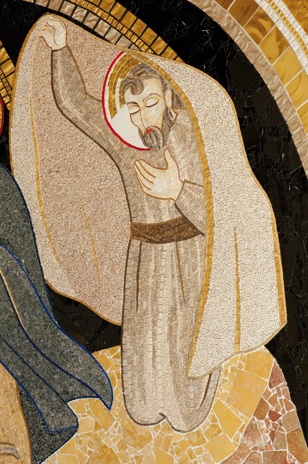 Mosaic artwork depicting Jesus Christ with a halo, with one hand on his chest and the other raised in blessing, surrounded by geometric patterns in gold, black, and beige tiles.