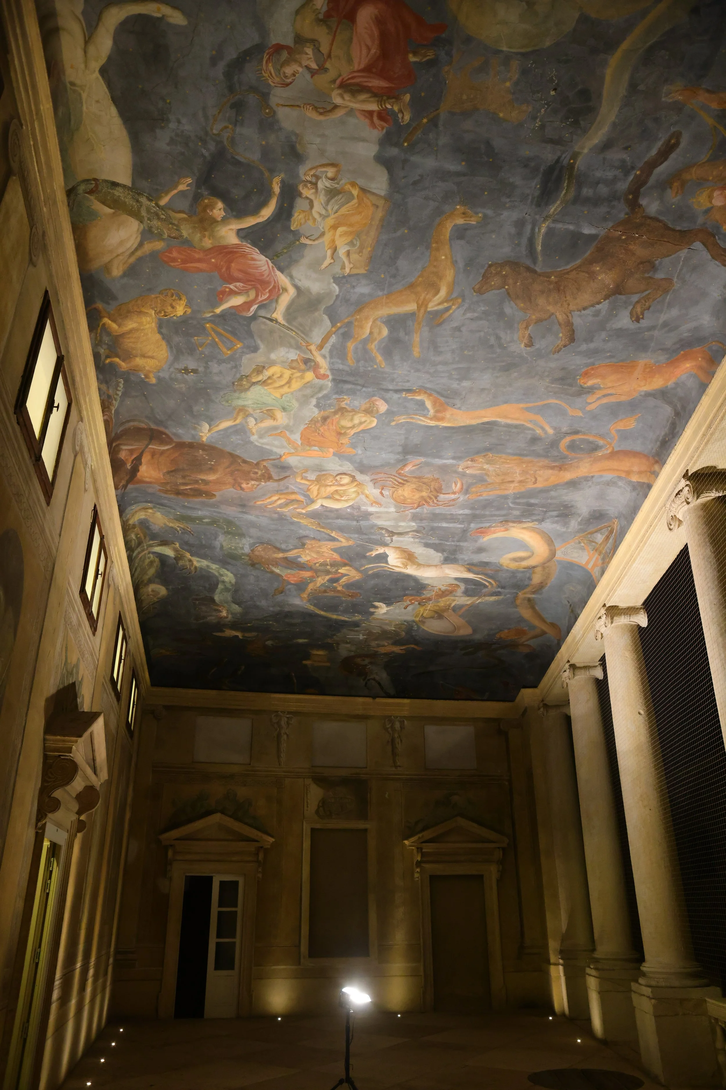 A large ceiling mural depicting mythological figures and animals, including a chariot drawn by horses, in a classical style.