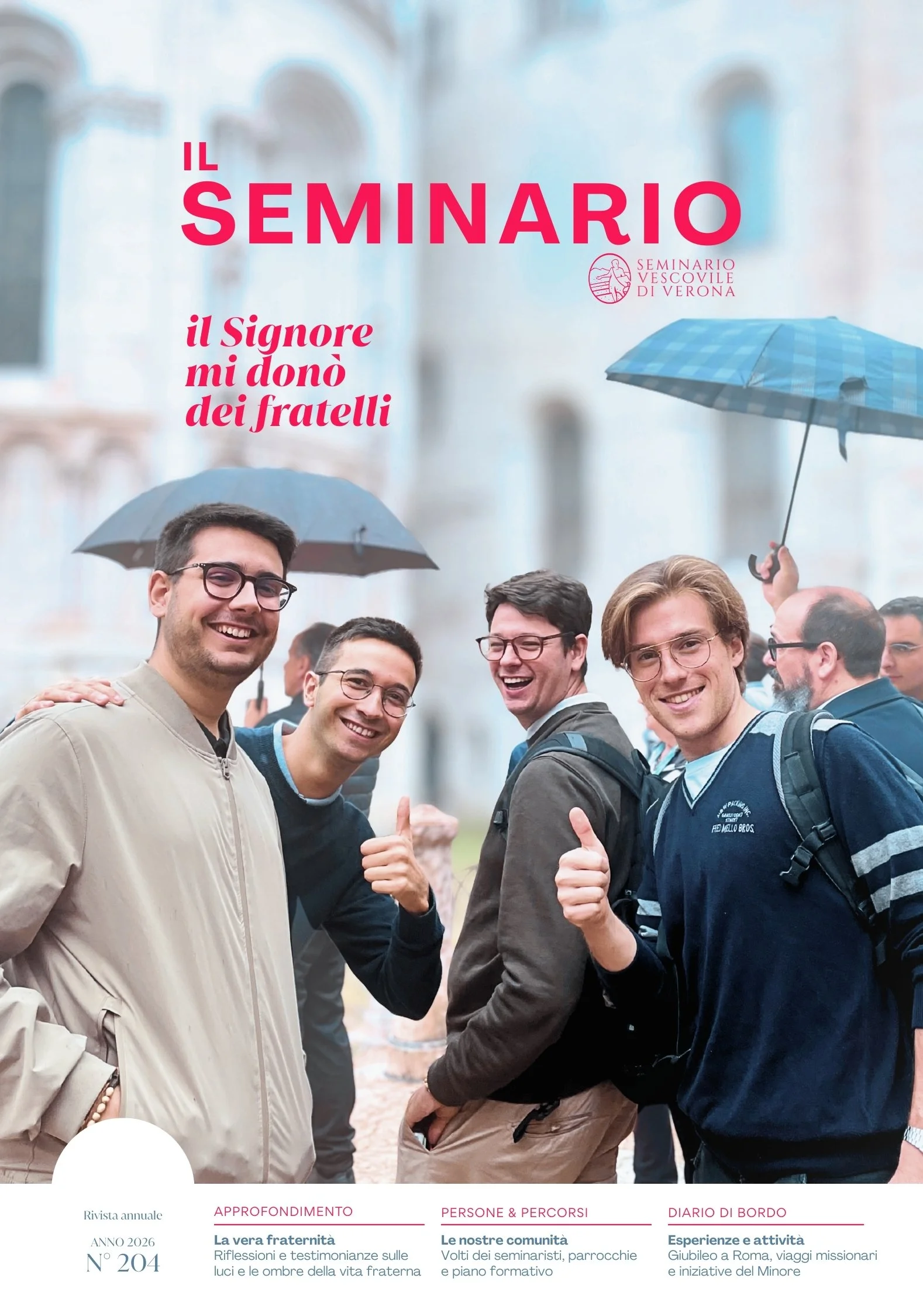 A group of smiling young men with backpacks, some holding umbrellas, gathered outdoors on a rainy day, with blurred historic buildings in the background.