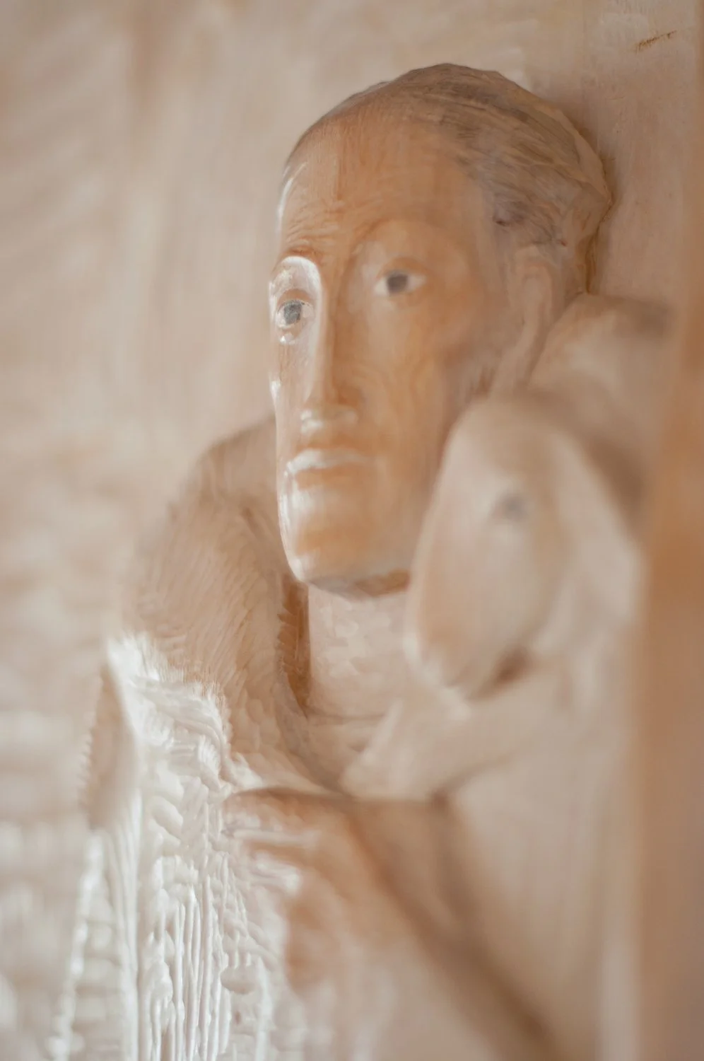 Close-up of a carved wooden sculpture of a man's face, showing detailed features like eyes, nose, and mouth.