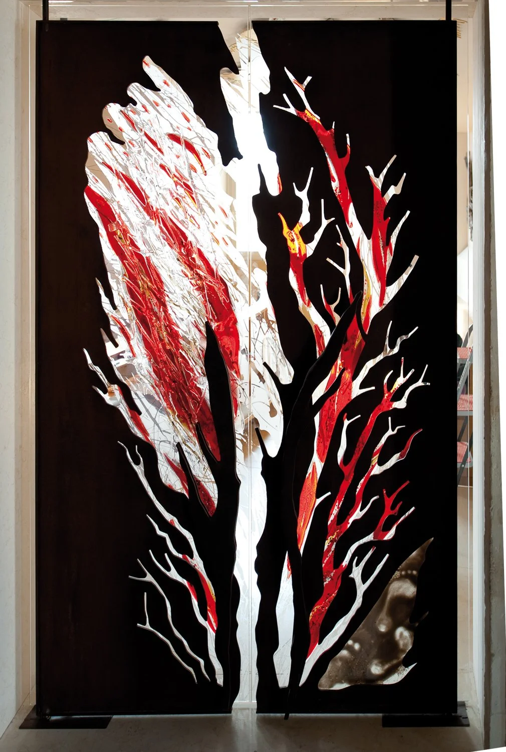 Decorative black metal screen with a silhouette of a tree with red and white abstract leaves.