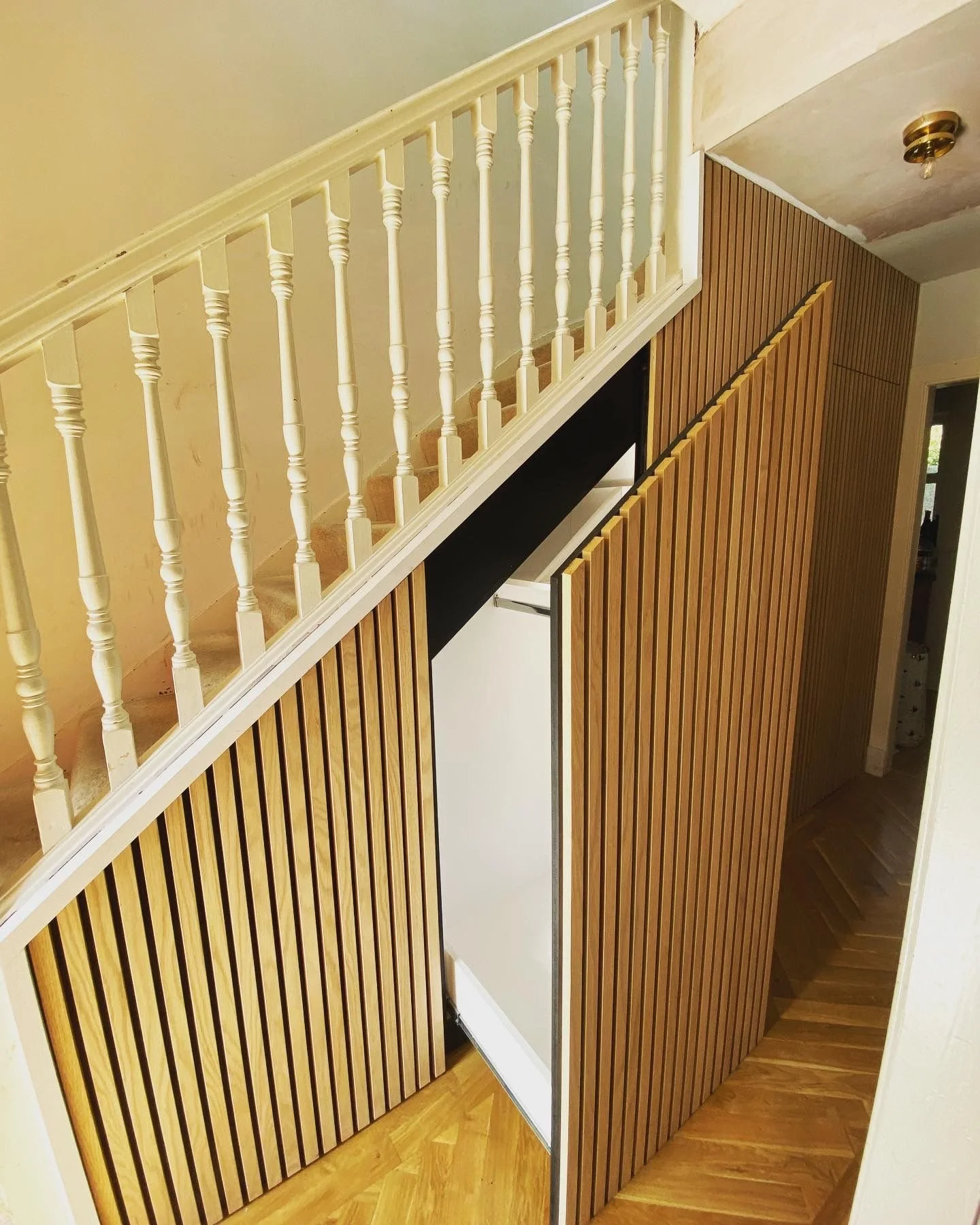 View of a staircase revealing a hidden storage drawer, behind vertical wooden slats.