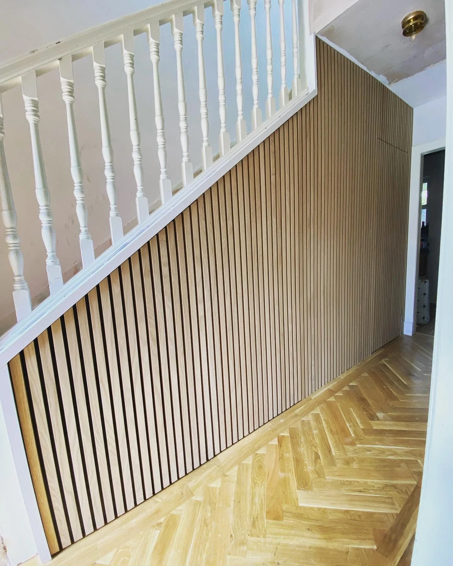Interior of a house with a wooden slat wall and white railing staircase.