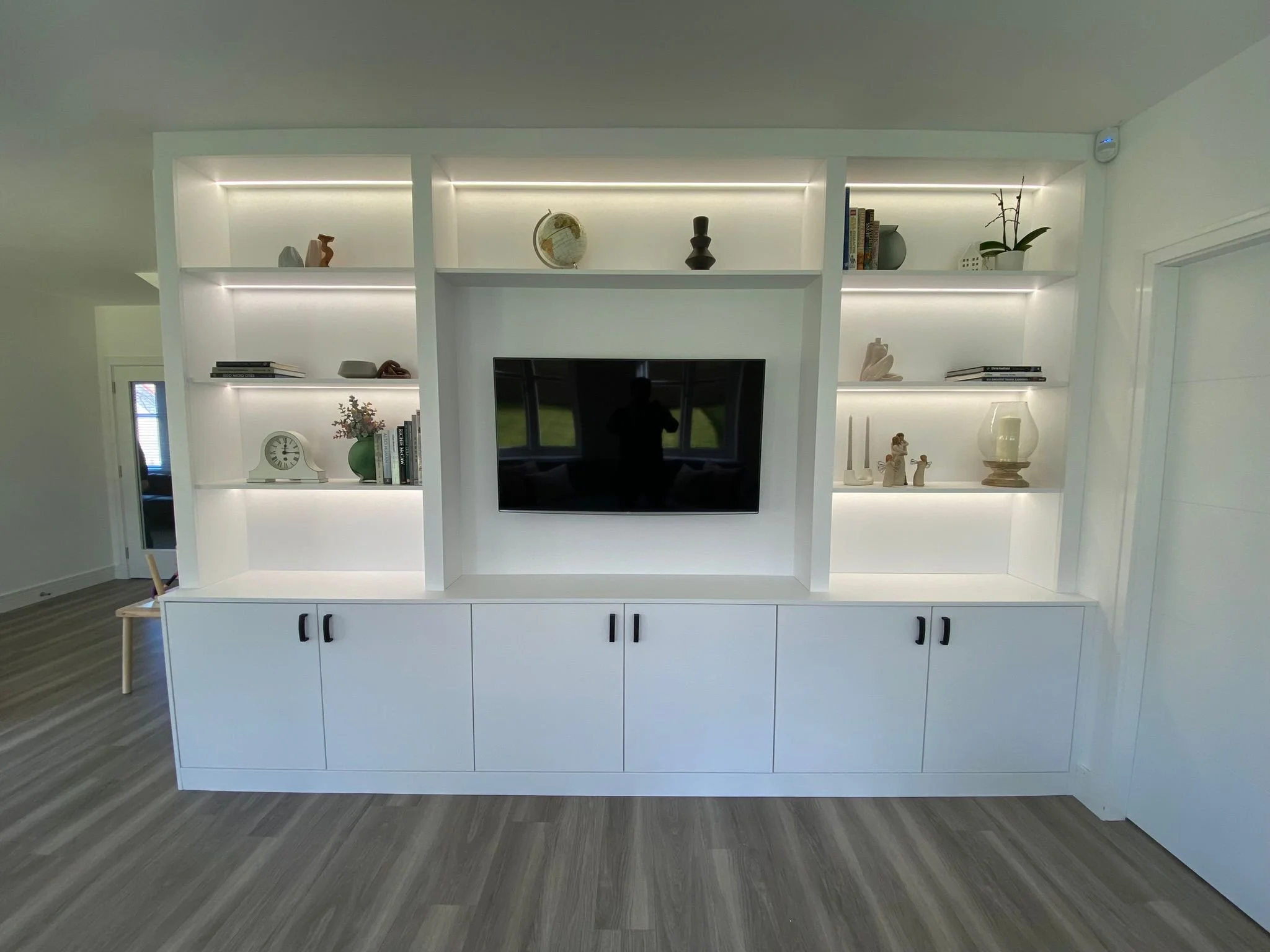 White built-in media wall with TV and display shelving.