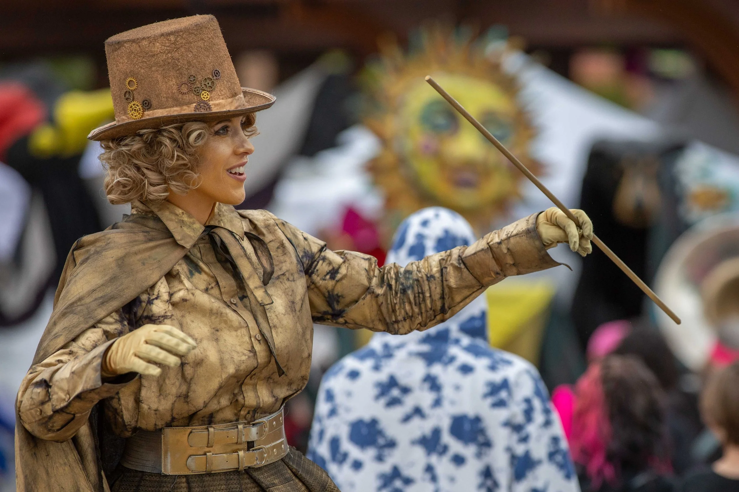 Crowd of people at an outdoor event with vendor tents and green decorations, suggesting a festival or celebration.