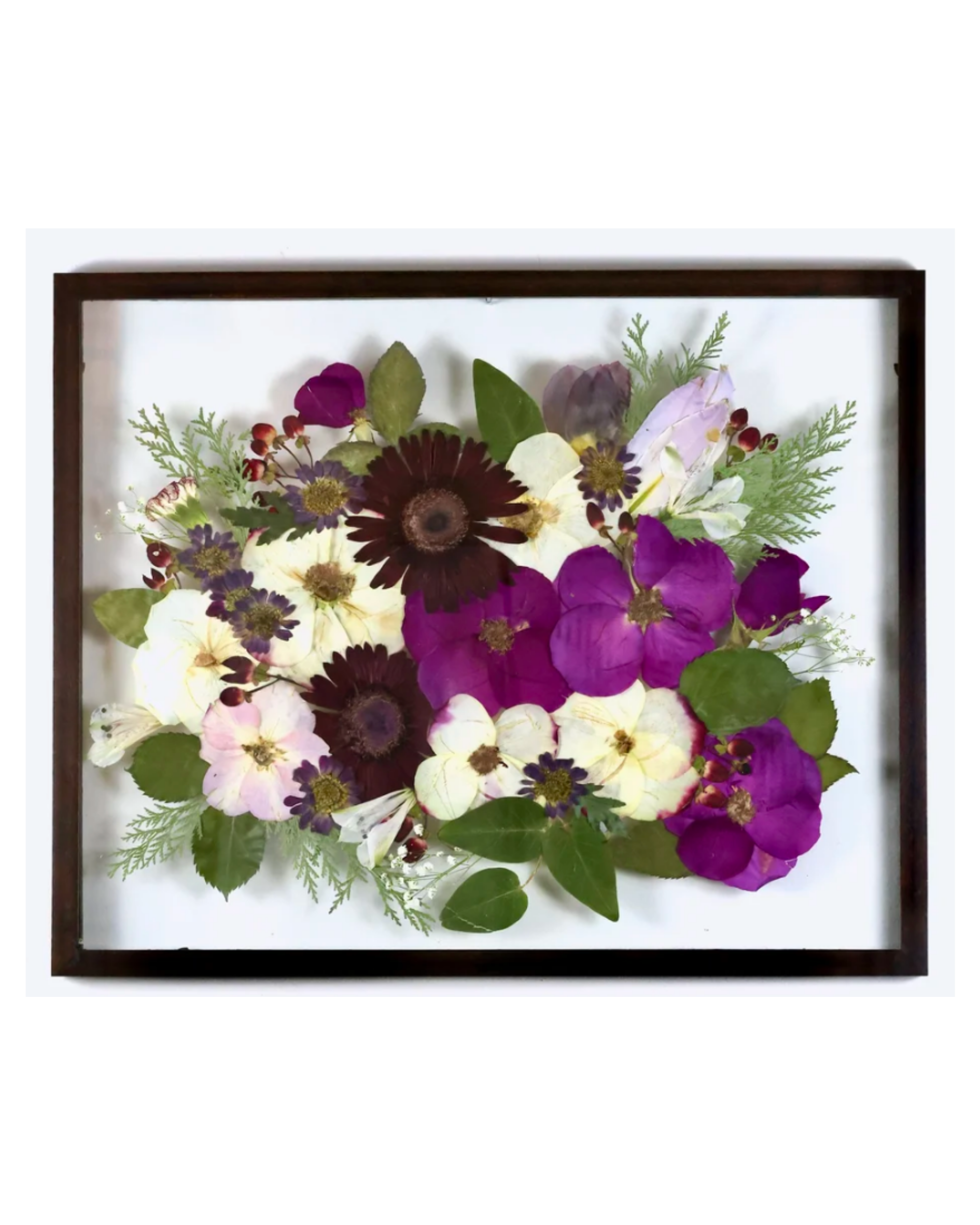 A floral arrangement featuring pink, purple, and white flowers with green leaves, displayed in a black frame.