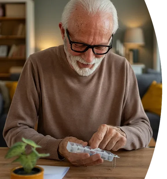 Elderly man reviewing prescription medications at home supported by a patient assistance program.