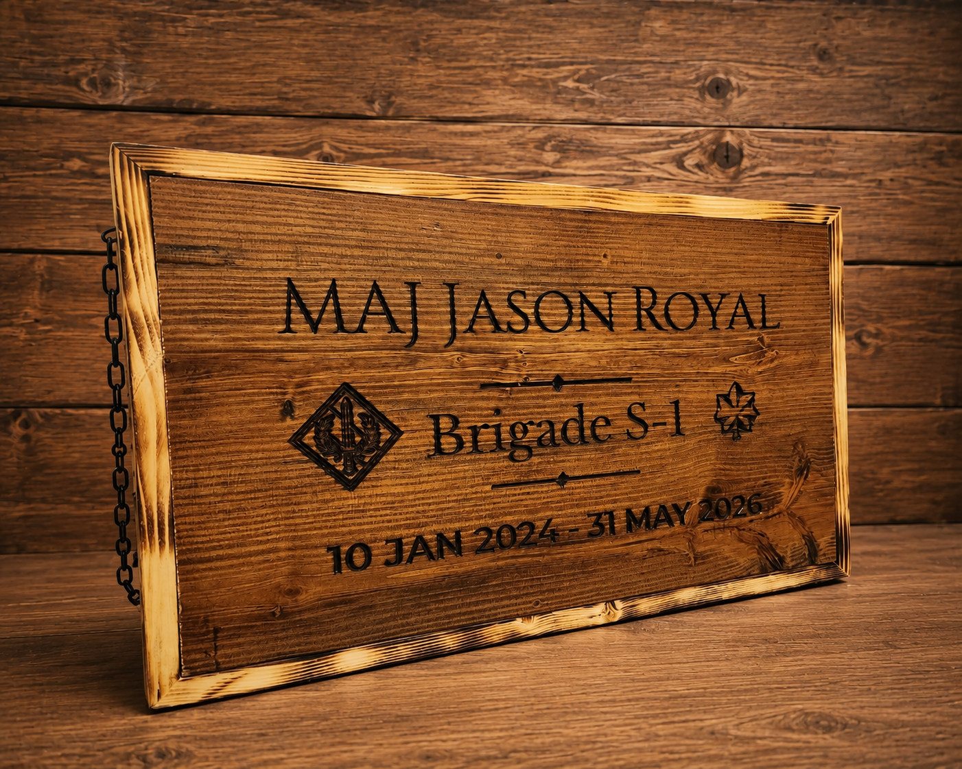 Farewell sign, Brigade S-1: engraved name, unit crest, rank and service dates on stained pine, with a torched frame and hanging chain.