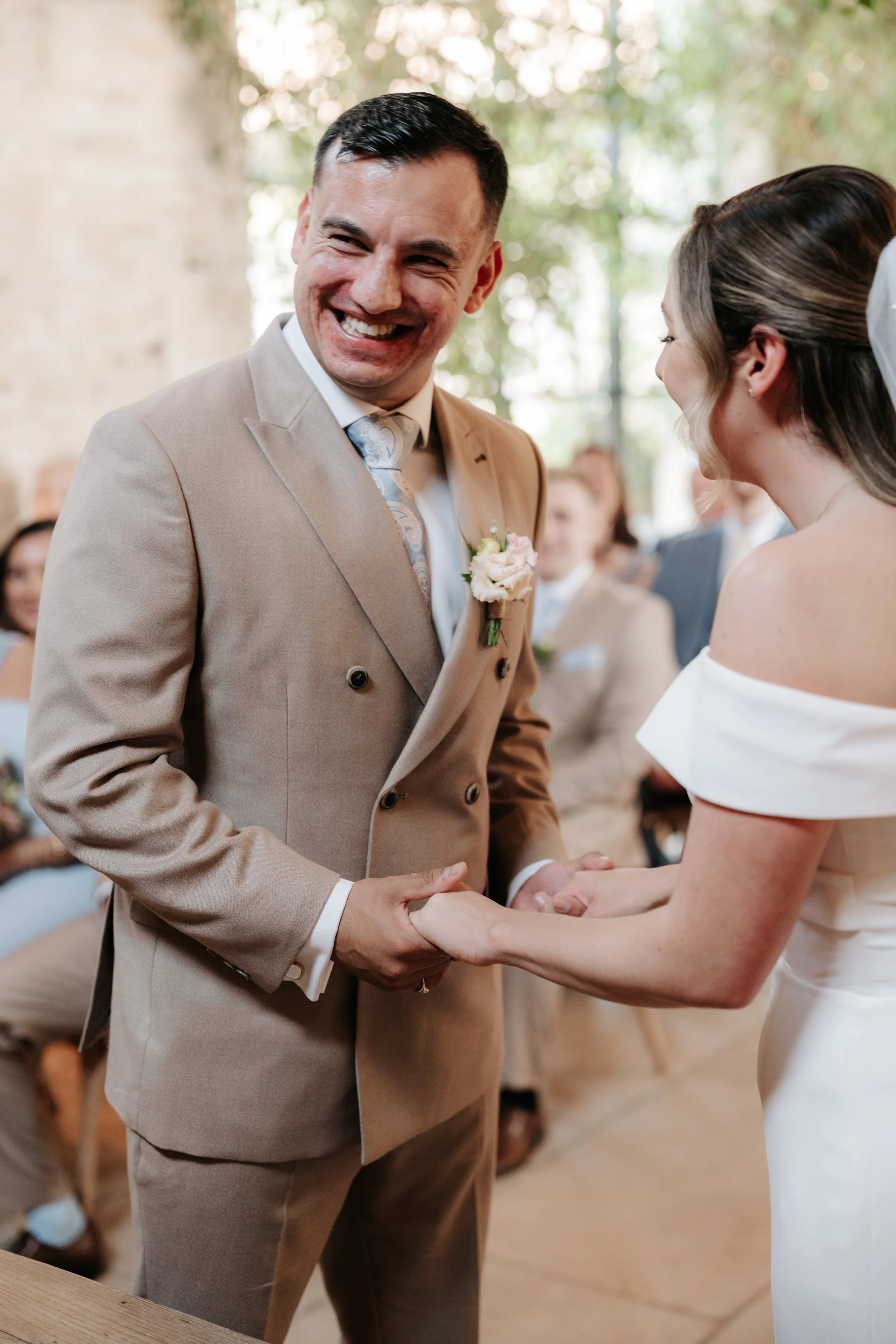 A man and woman holding hands during a wedding ceremony, smiling at each other.