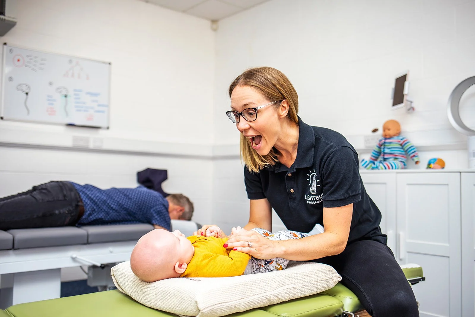 Sarah Keen smiles at a baby during his chiropractic adjustment at Lightbulb Chiropractic.