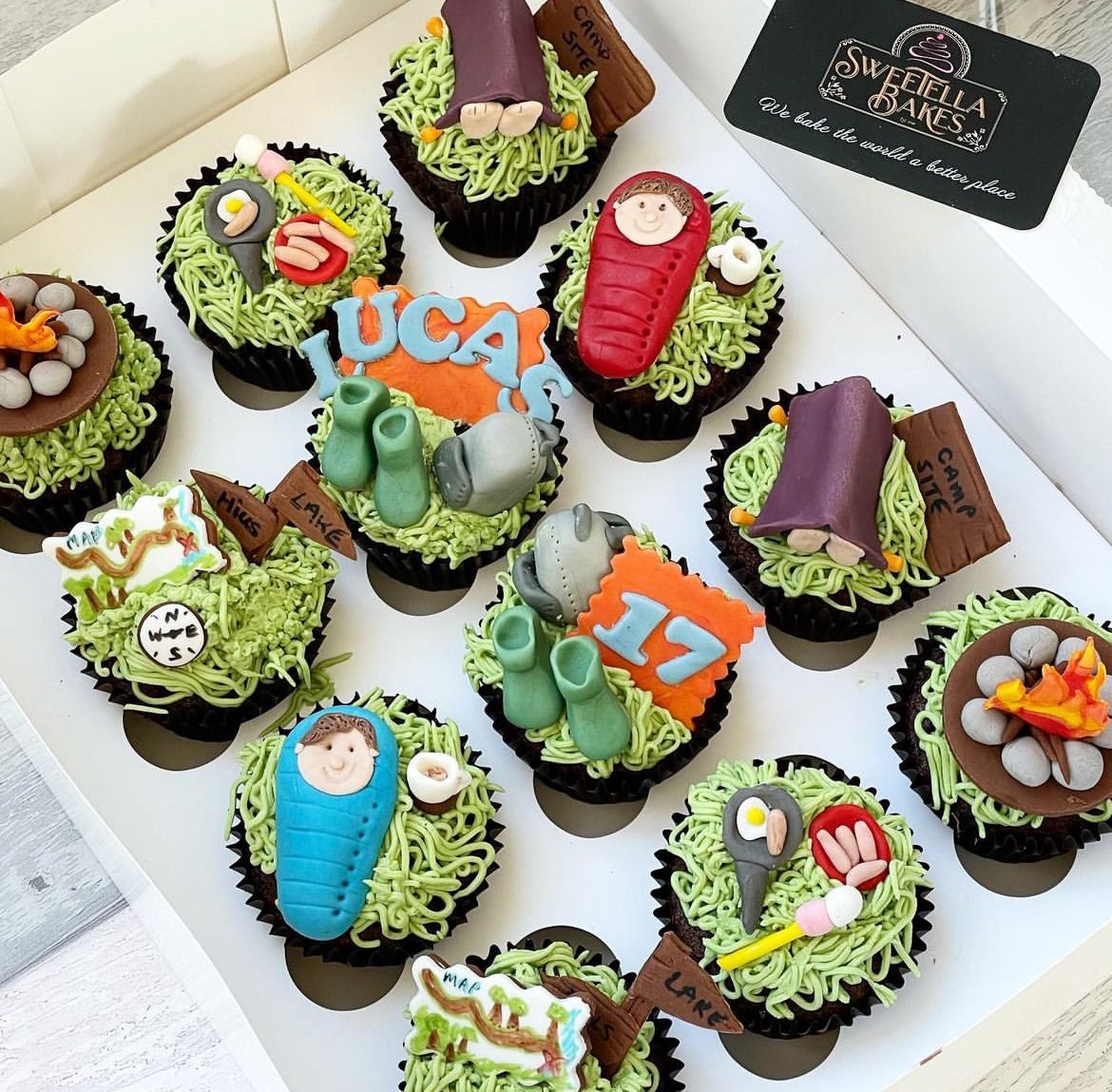 Cupcakes decorated with theme of camping, hiking, and outdoor activities, featuring edible fondant decorations of gear, maps, and nature elements.