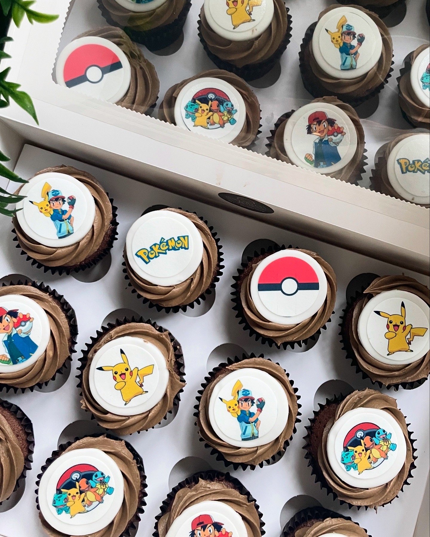 Cupcakes decorated with Pokémon images including Pikachu, Ash Ketchum, Pokéballs, and the Pokémon logo.