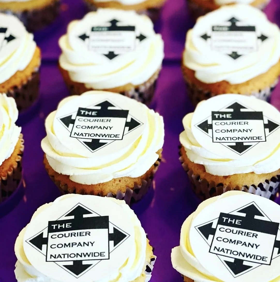 Cupcakes with white frosting and a black and white logo that reads 'The Courier Company Nationwide' on top.