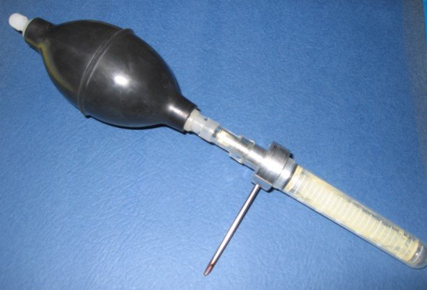 A device called a cyclone pollinator, with tubing, and a needle, used for spraying pollen into pollination bags for controlled tree breeding.