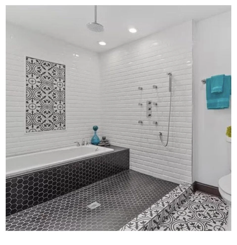 Modern bathroom with a walk-in shower, bathtub, and patterned tile floor and wall accents.