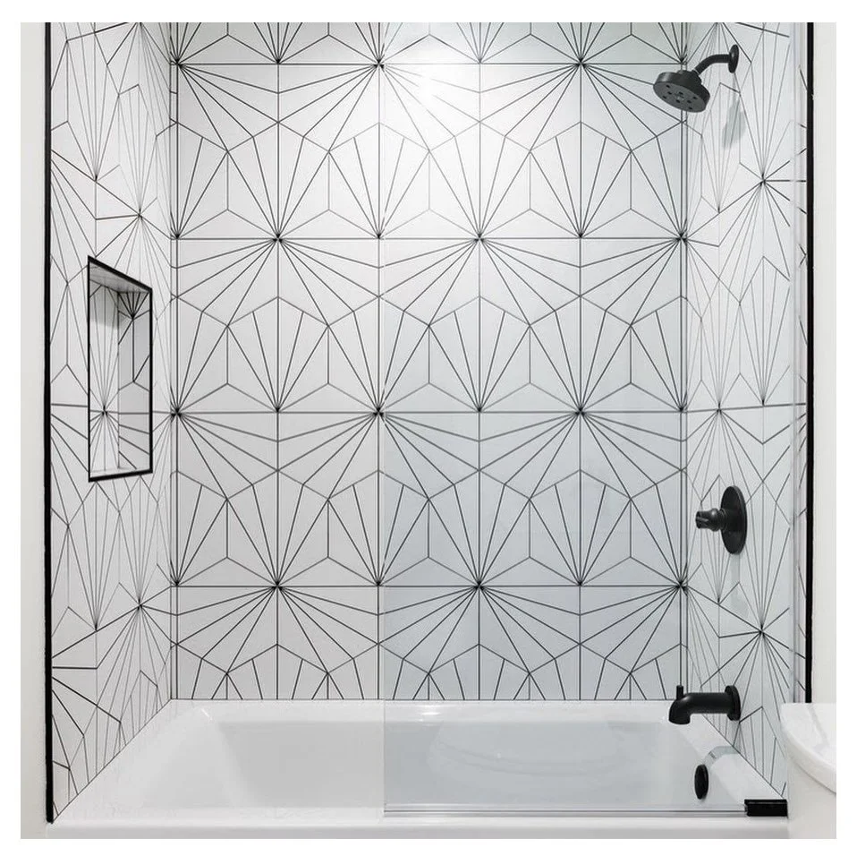 Modern shower with geometric black and white tile pattern, black showerhead, and black fixtures.
