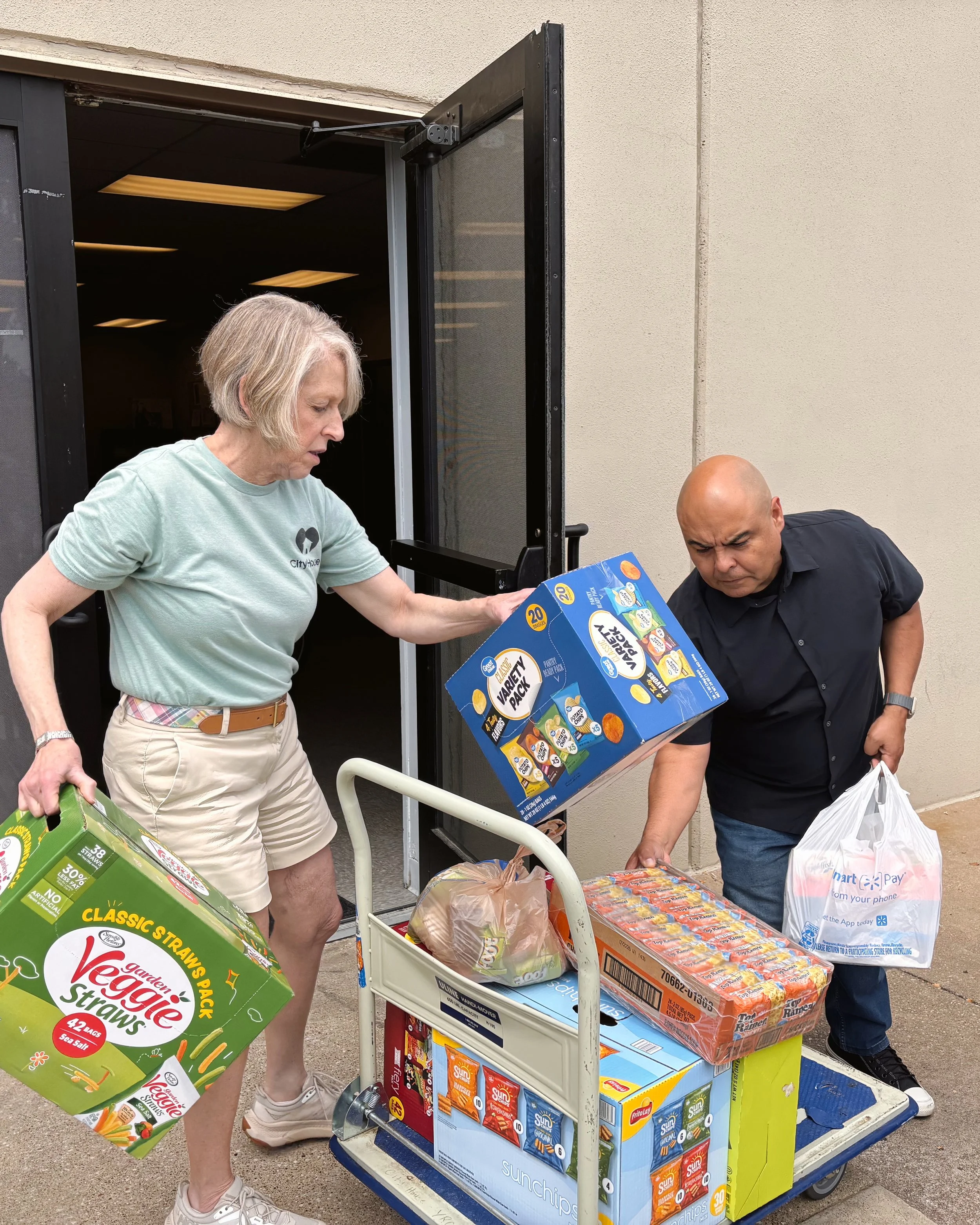 Two people unloading grocery carts outside a building