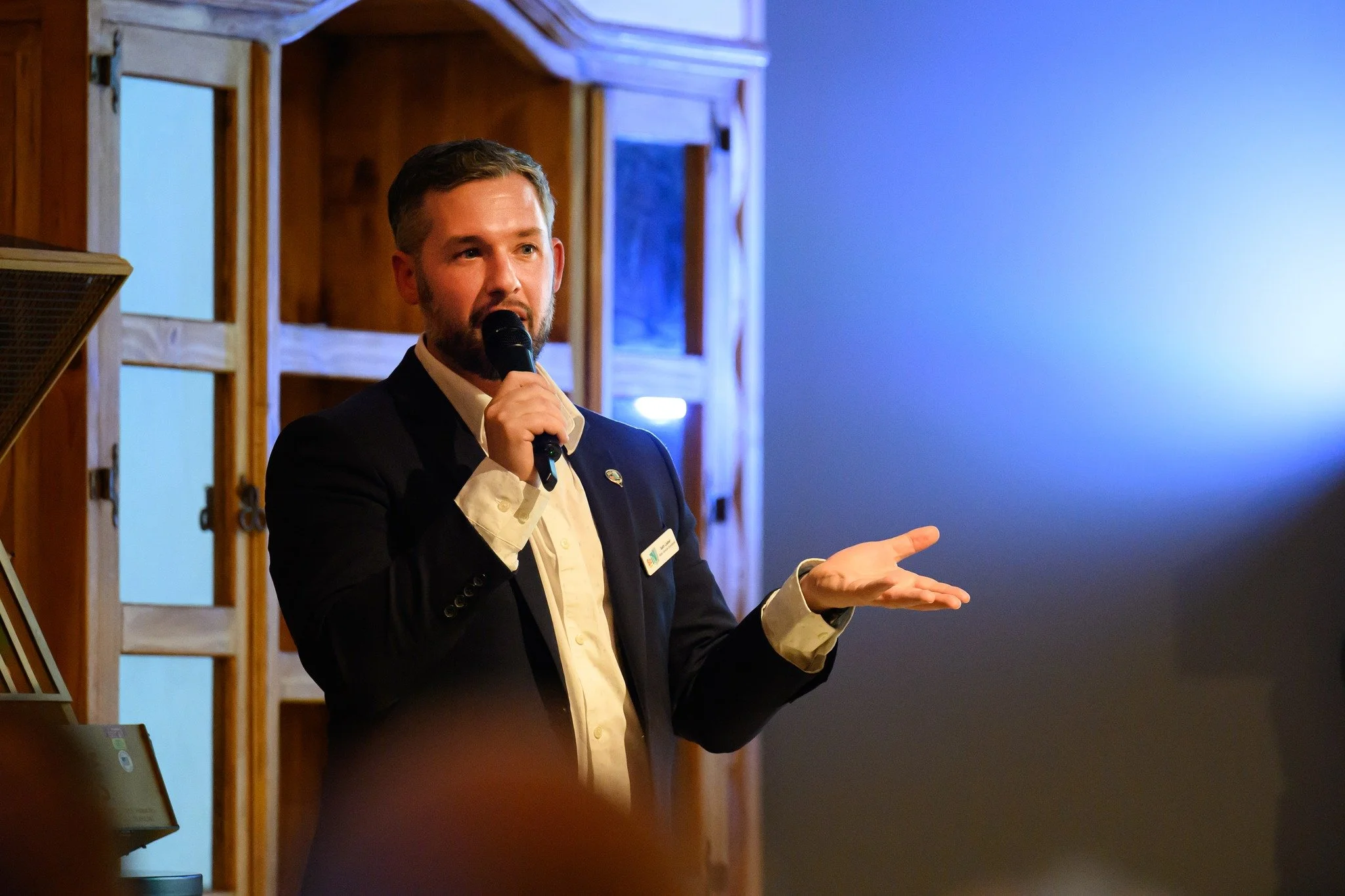 Seth Lieber speaking at a live event, engaging the audience with a handheld microphone.