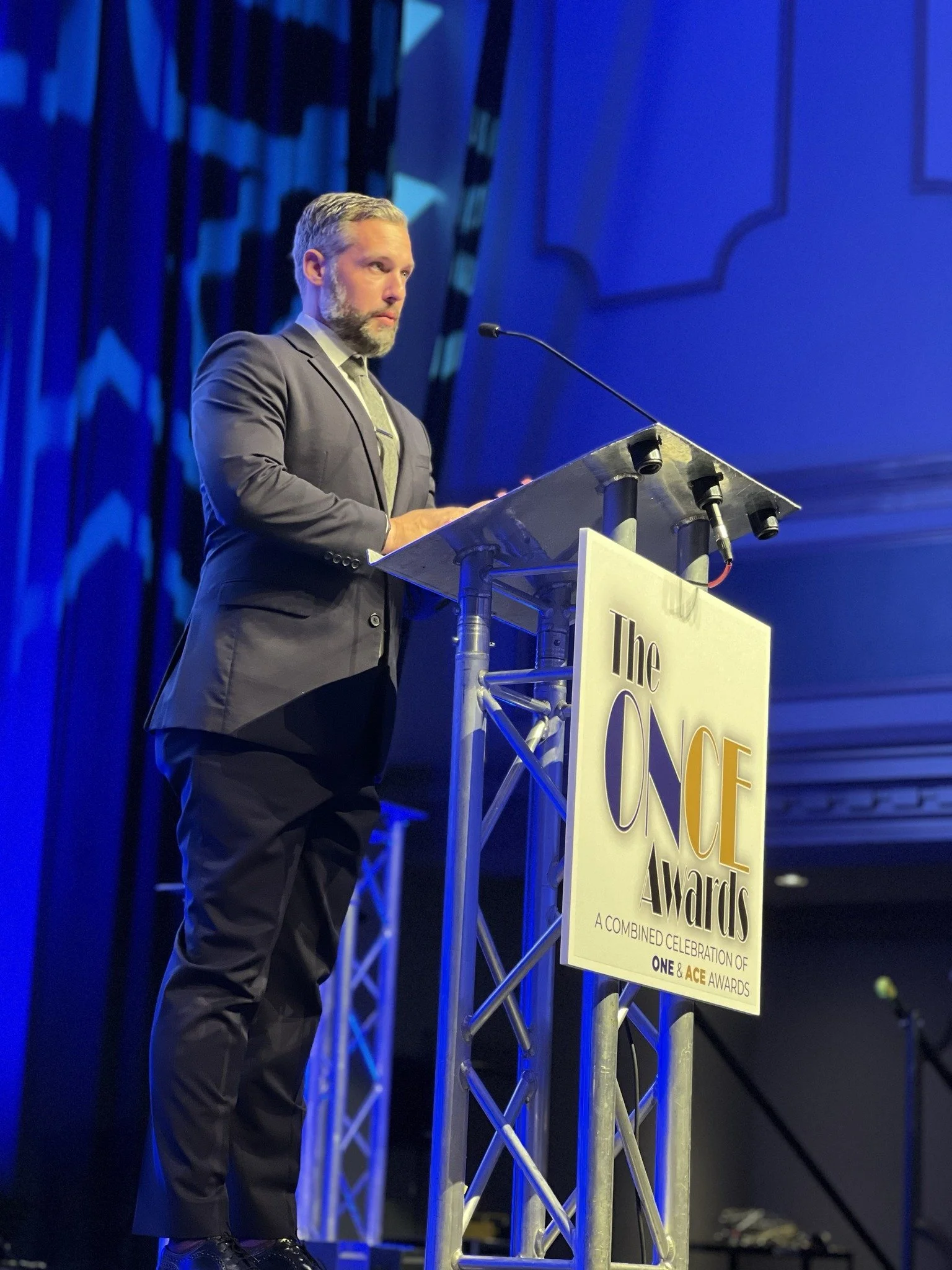 Seth Lieber delivering a presentation from the stage at a conference podium.
