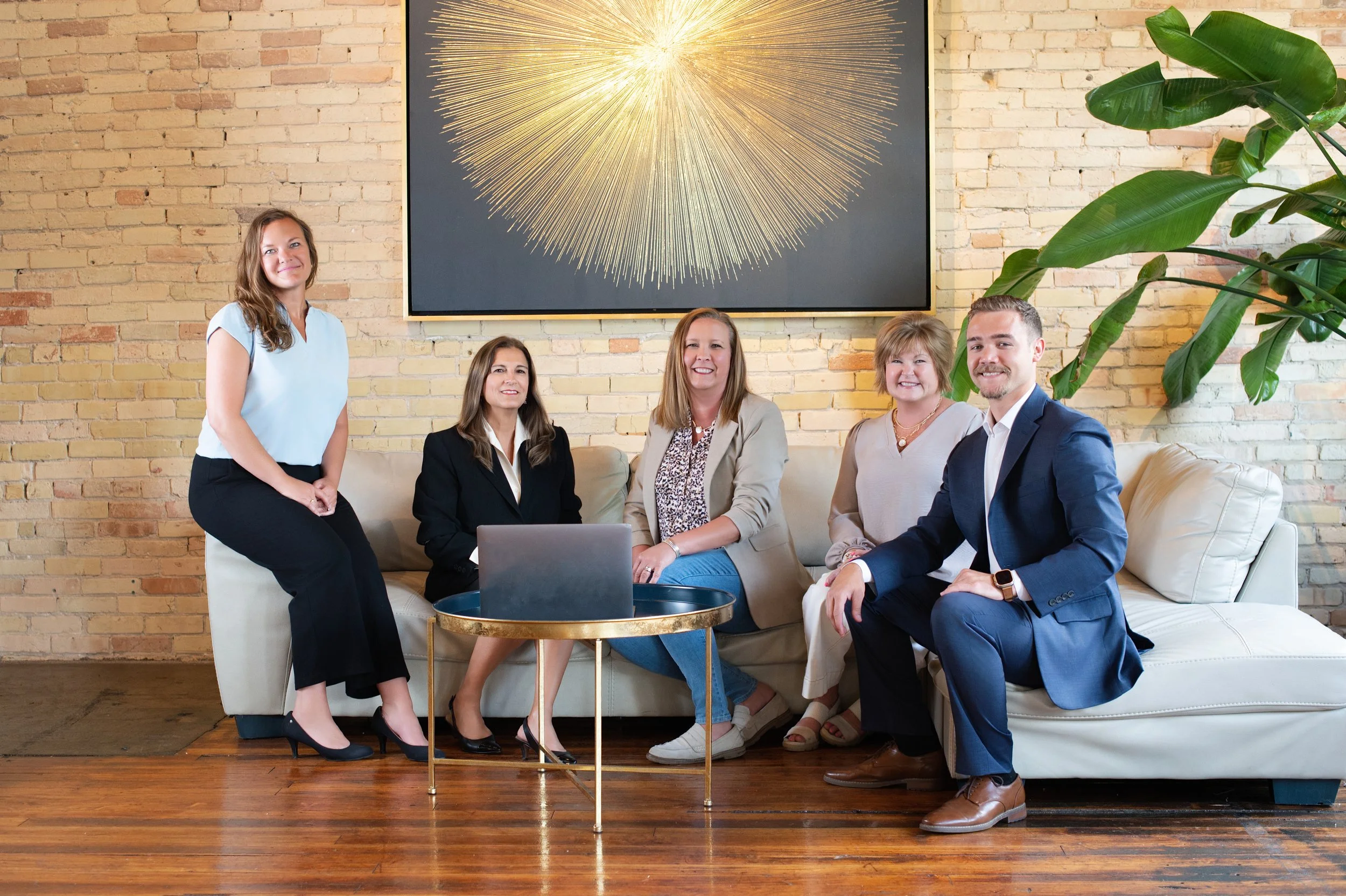 The team from Snider & Co real estate services who serve clients in West Michigan and the greater Grand Rapids area, sitting on a white sofa in a modern office.