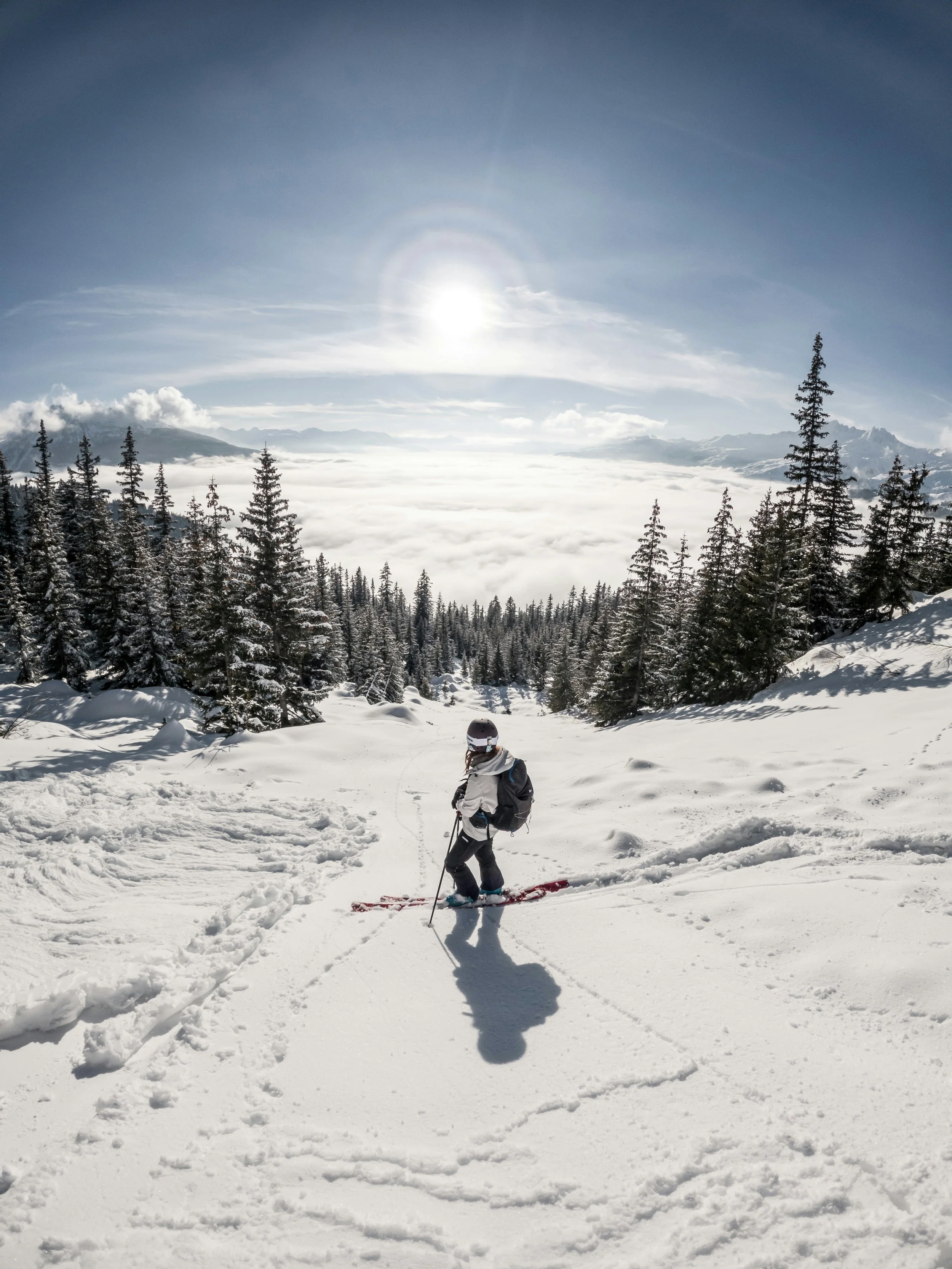 Personne faisant du ski dans un paysage enneigé avec des montagnes et un ciel clair.