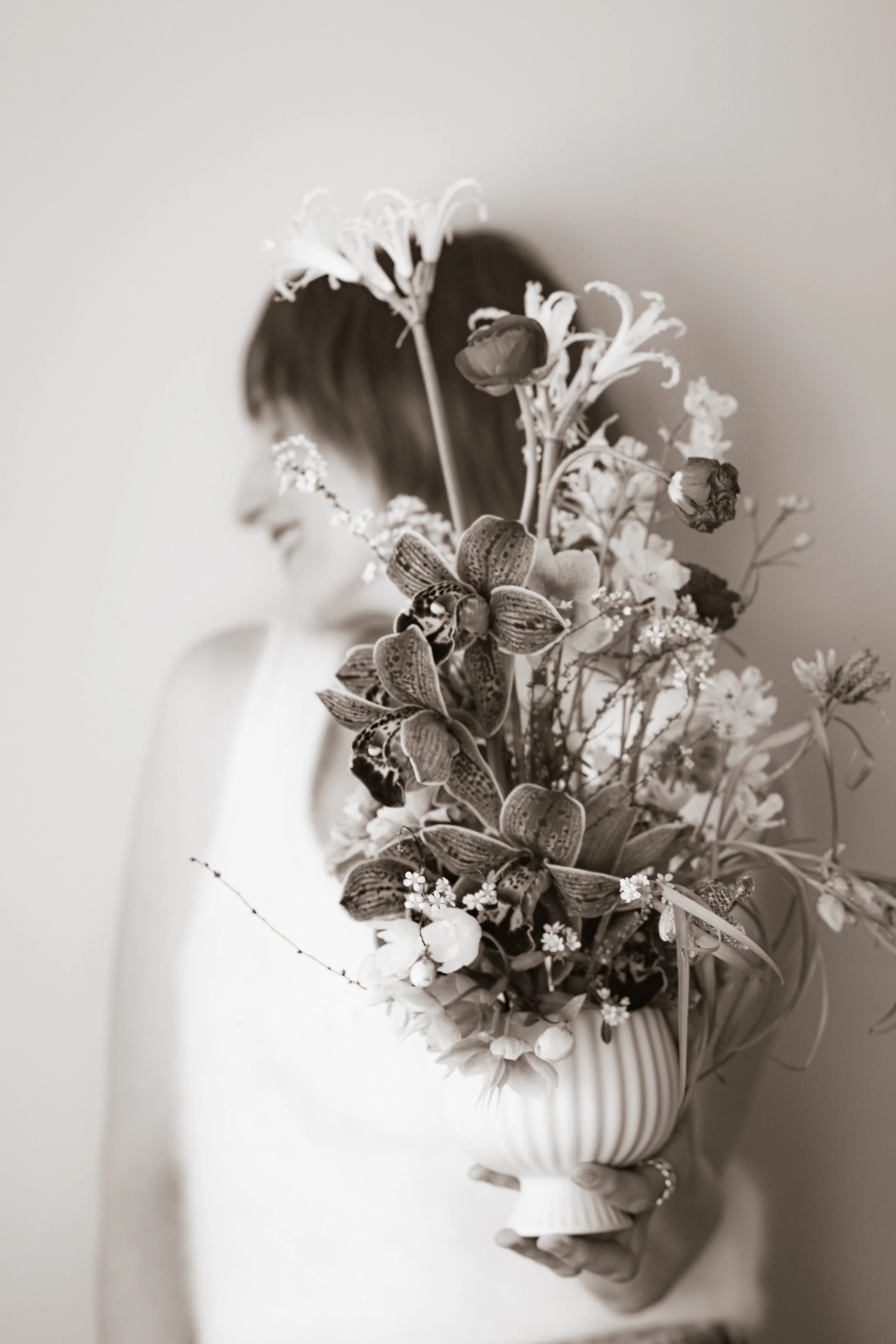 Woman beside a floral arrangement, evoking the thoughtfulness of gifting a Human Design reading