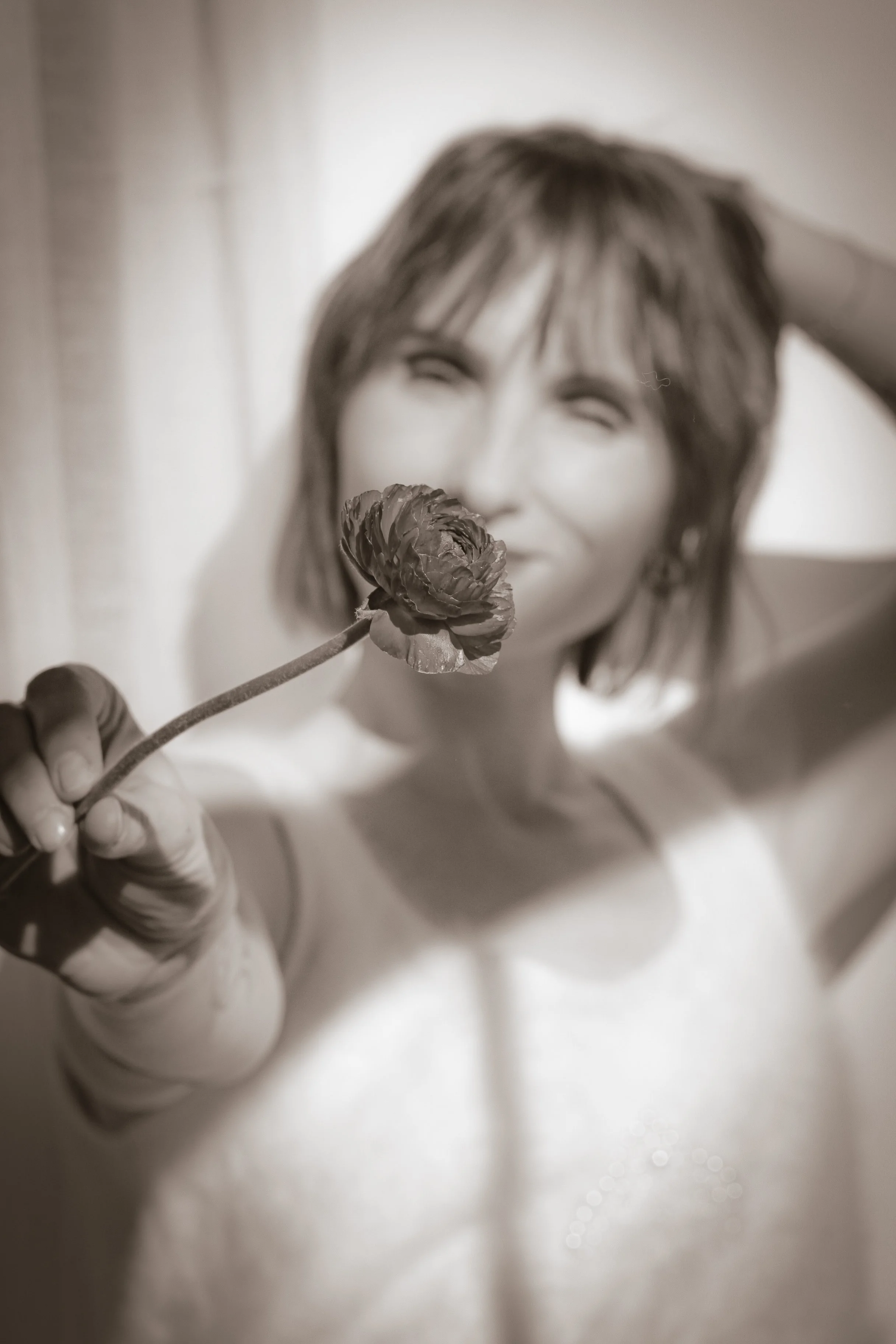 Natasha Yaroshenko holding a flower, in a soft focused portrait for her private mentorship program