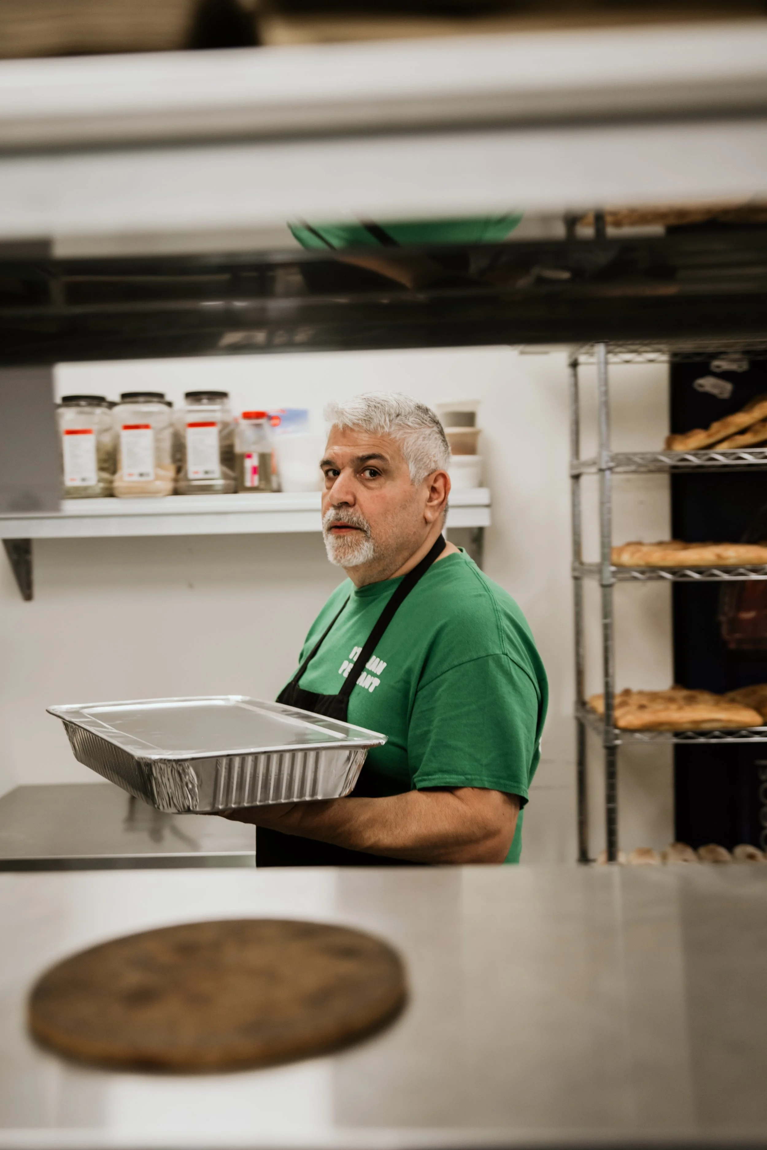 Man holding lasagna tray, chicken parm tray, veal parm tray.