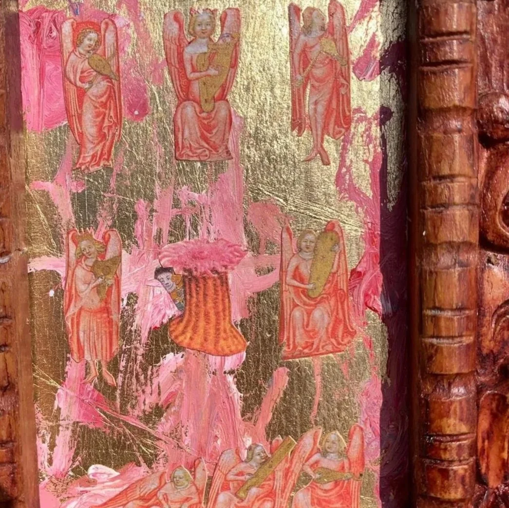 Detalle de un texto religioso con ilustraciones de ángeles y santos, enmarcado con madera tallada