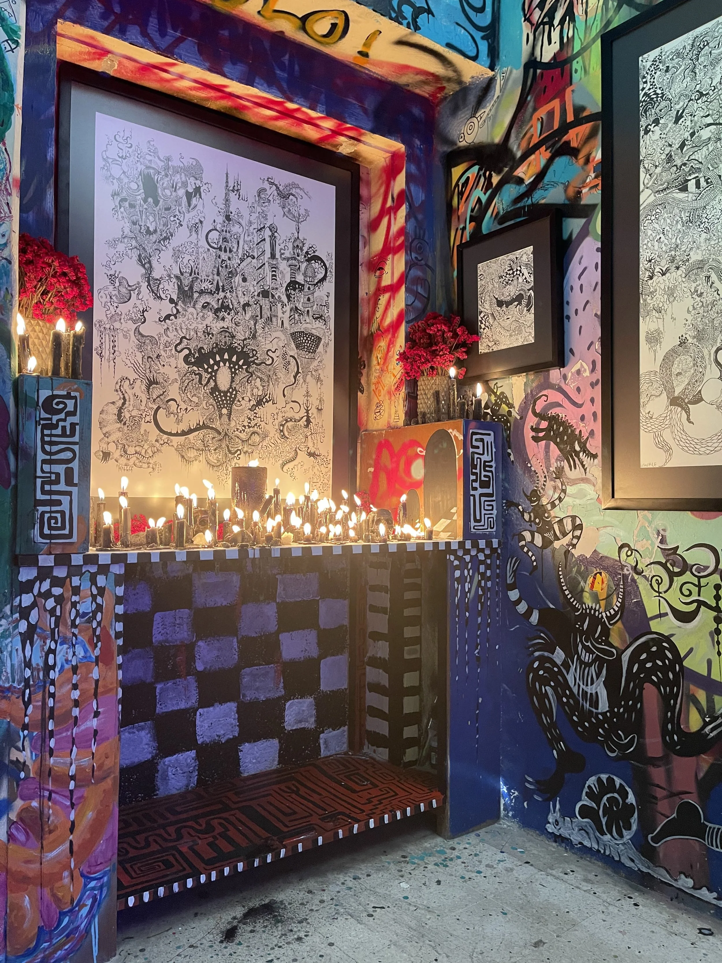 Altar con velas, cuadros y murales coloridos en un ambiente artístico y vibrante.