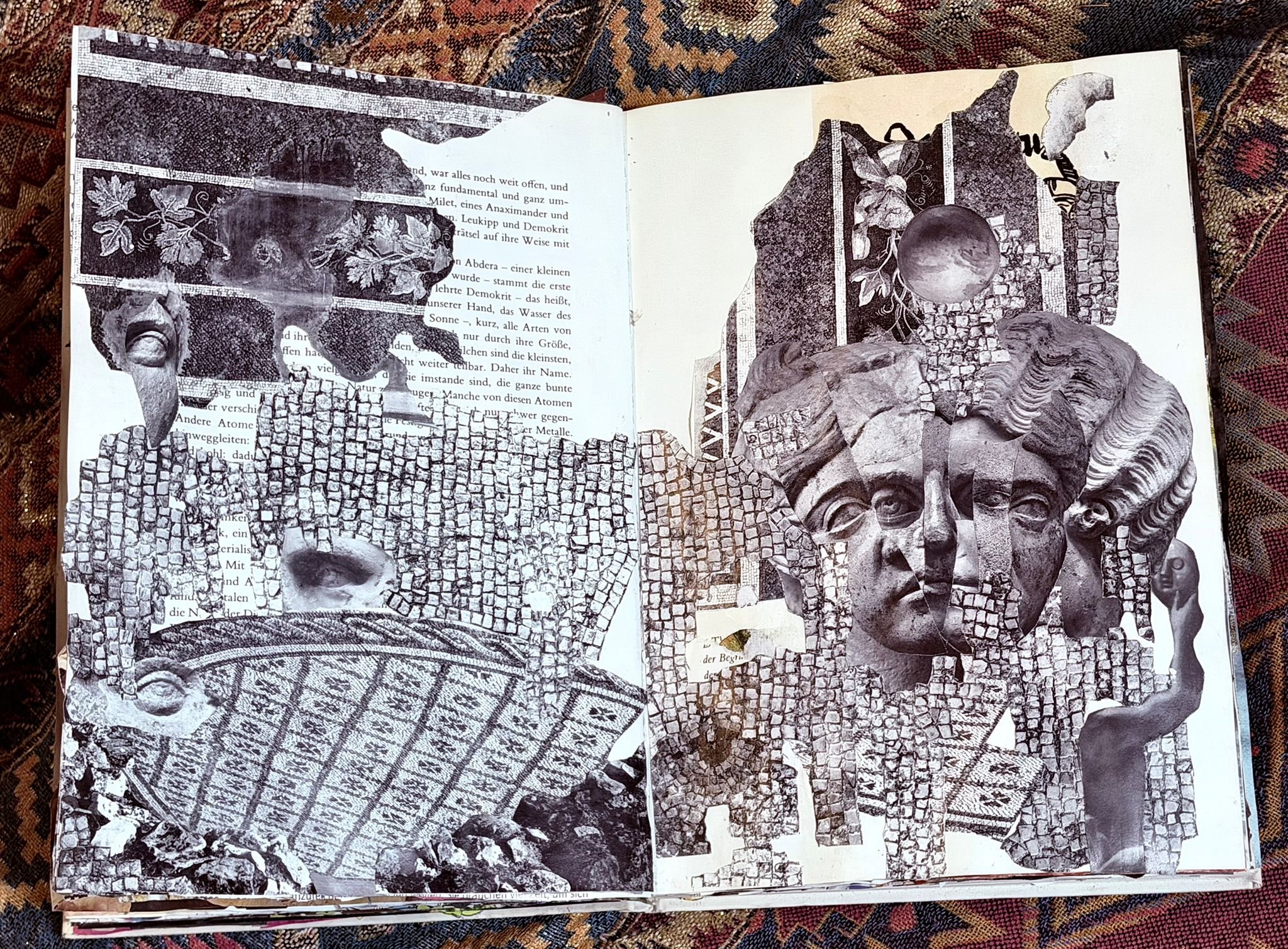 Libro abierto con recortes y dibujos en blanco y negro, incluyendo busto de una cabeza, hojas, un globo terráqueo y elementos arquitectónicos, sobre un fondo de tapete o alfombra con patrón geométrico.