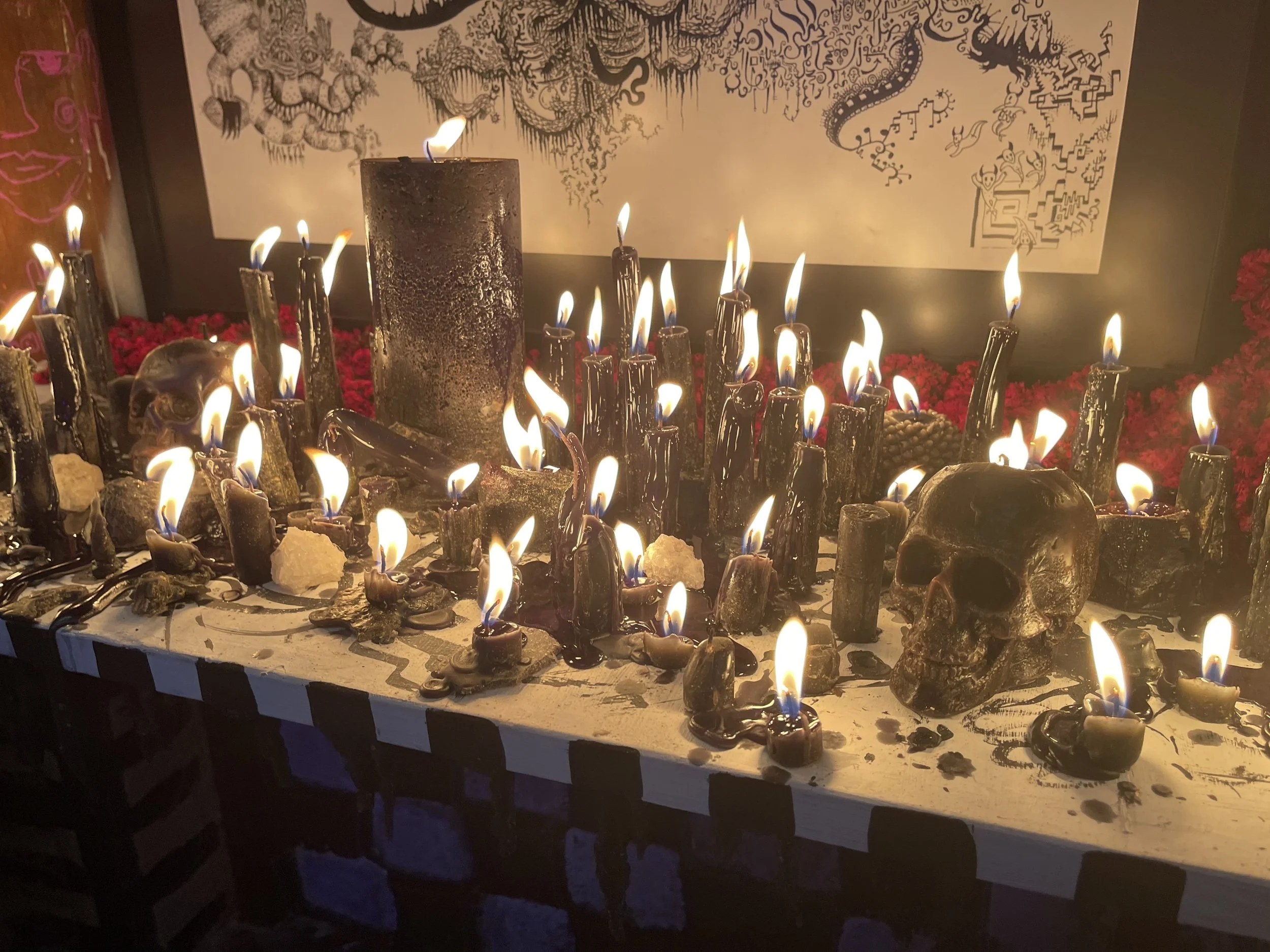 Altares con calaveras, velas encendidas y decoraciones tradicionales de Día de Muertos, con fondo de arte con serpientes y calaveras.