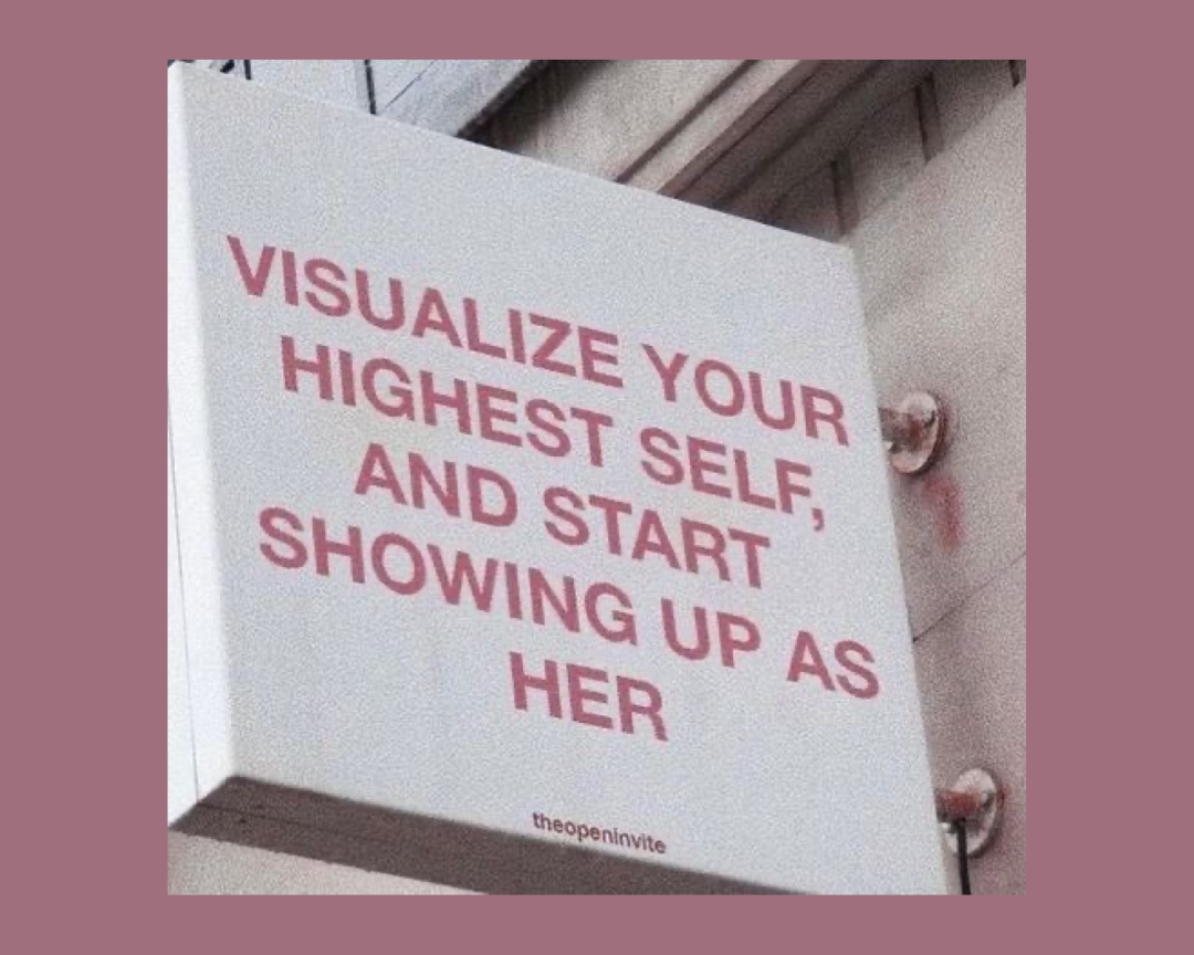 A sign with pink text on a white background that says, "Visualize your highest self, and start showing up as her."