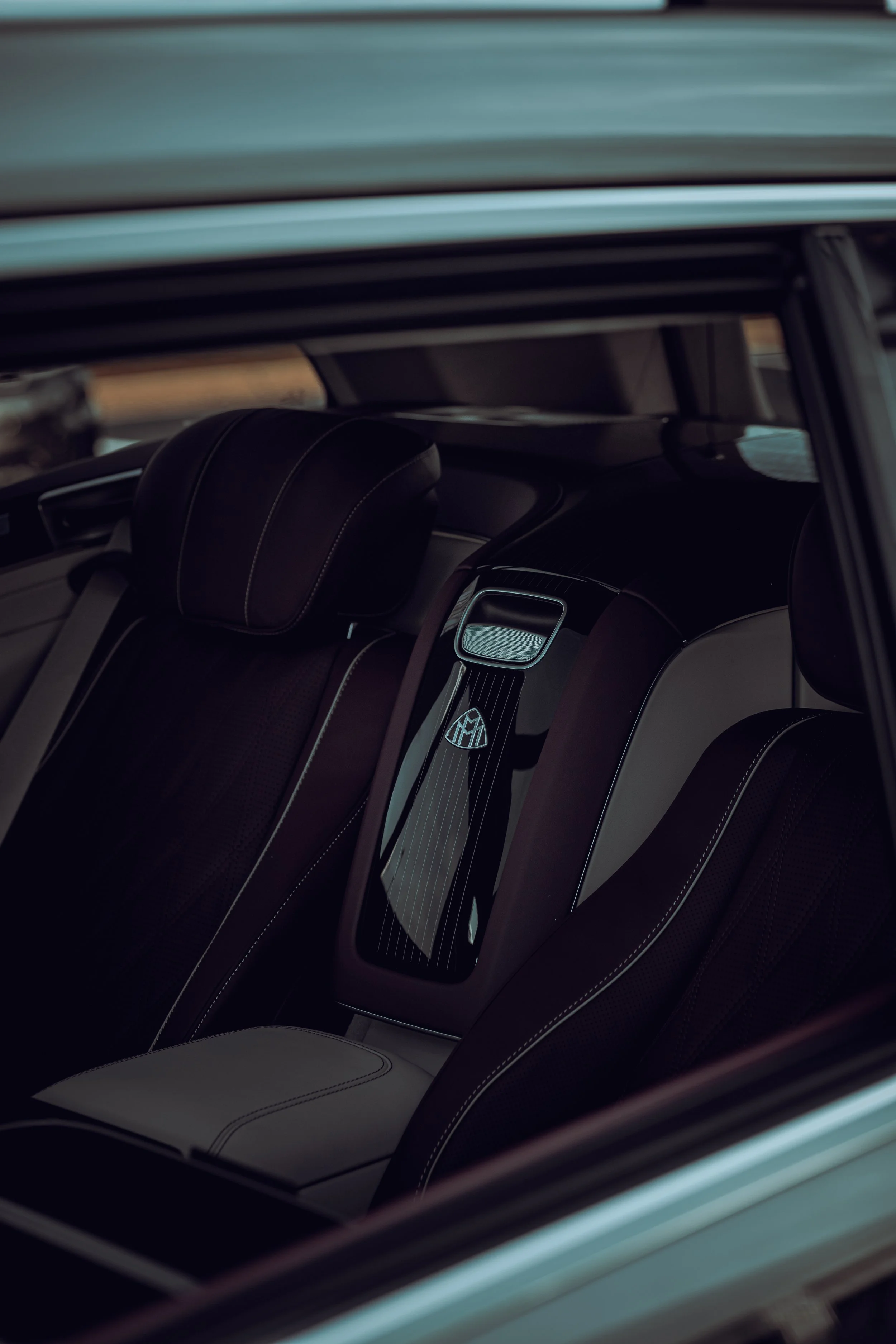 Close-up of a luxury car's interior with leather seats and a central control panel featuring a Mercedes-Benz logo.