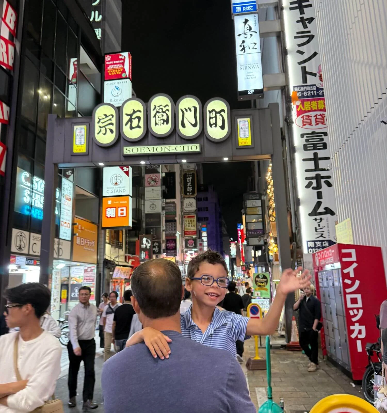 Father carrying his son through the illuminated Soemon-cho district in Osaka, Japan at night