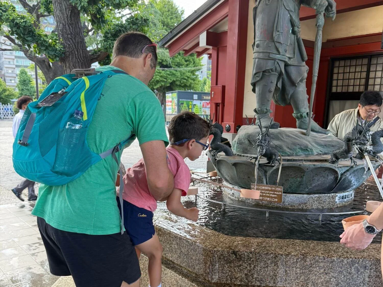 Father helping son wash his hands at Senso-ji temple in Tokyo, Japan.