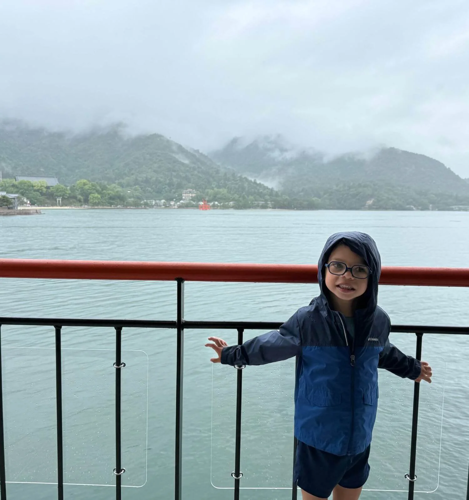 Jackson bundled up in his rain jacket aboard the ferry, torii gate behind him