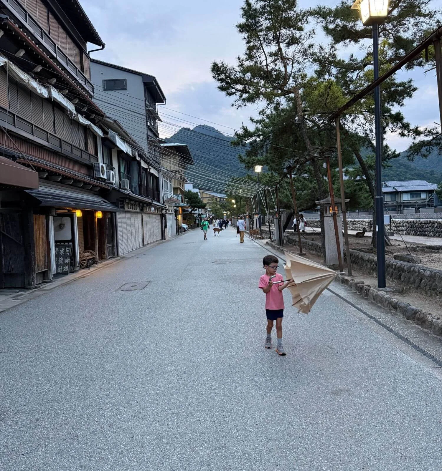 Jackson closing his umbrella as night falls on Miyajima's quiet streets